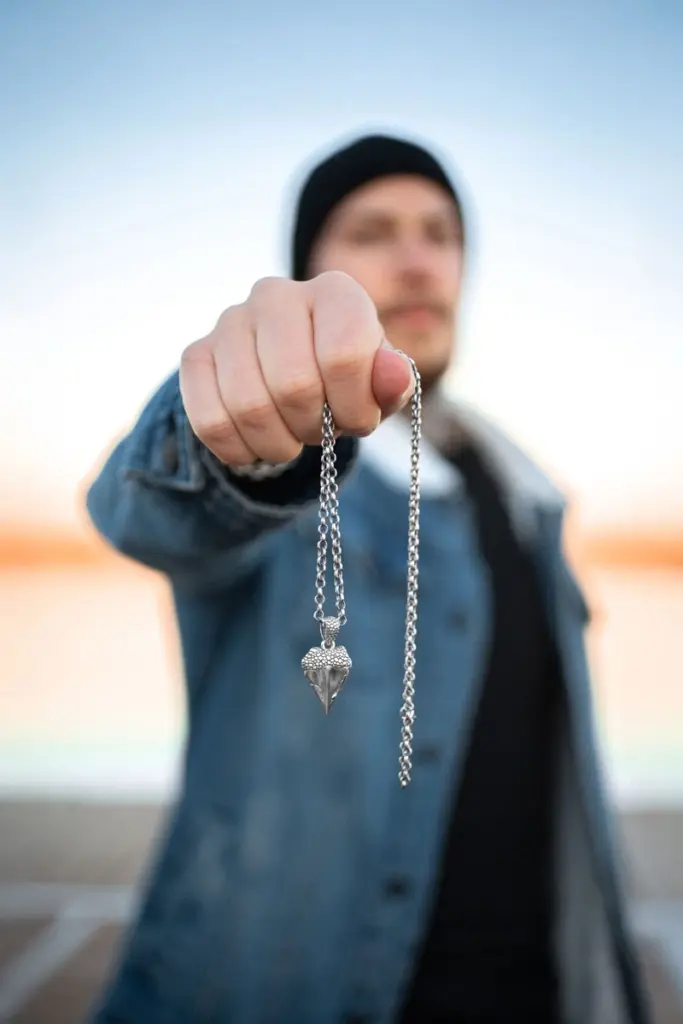 Mann hält eine Edelstahlkette mit großem, spitzen Anhänger