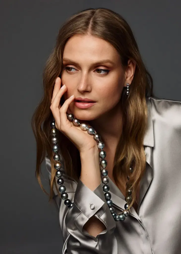 Dame mit langen braunen Haaren trägt eine große Perlenkette von GELLNER